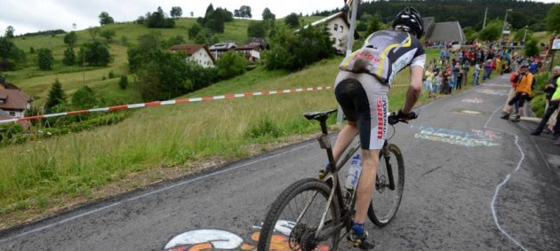 Mountainbiker, Fahrrad, Straßenkreide, Durchbeissen, Wiese, Flatterband, Zuschauer, Häuser, Schwarzwald, Hintern